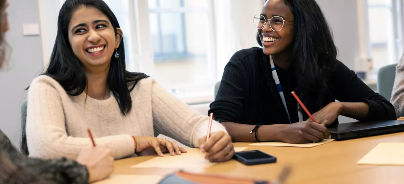 Två kvinnliga studenter sitter vid ett bord och skrattar. foto